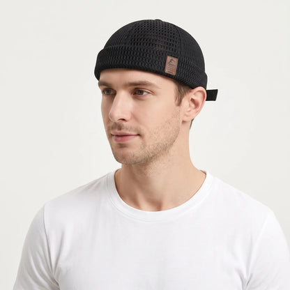 Man in a white t-shirt wearing the black open weave brimless cap with a small leather patch 24