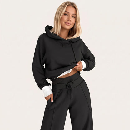 Model wearing the black tracksuit with contrasting white ribbed hem and cuffs, one hand in her pocket 25
