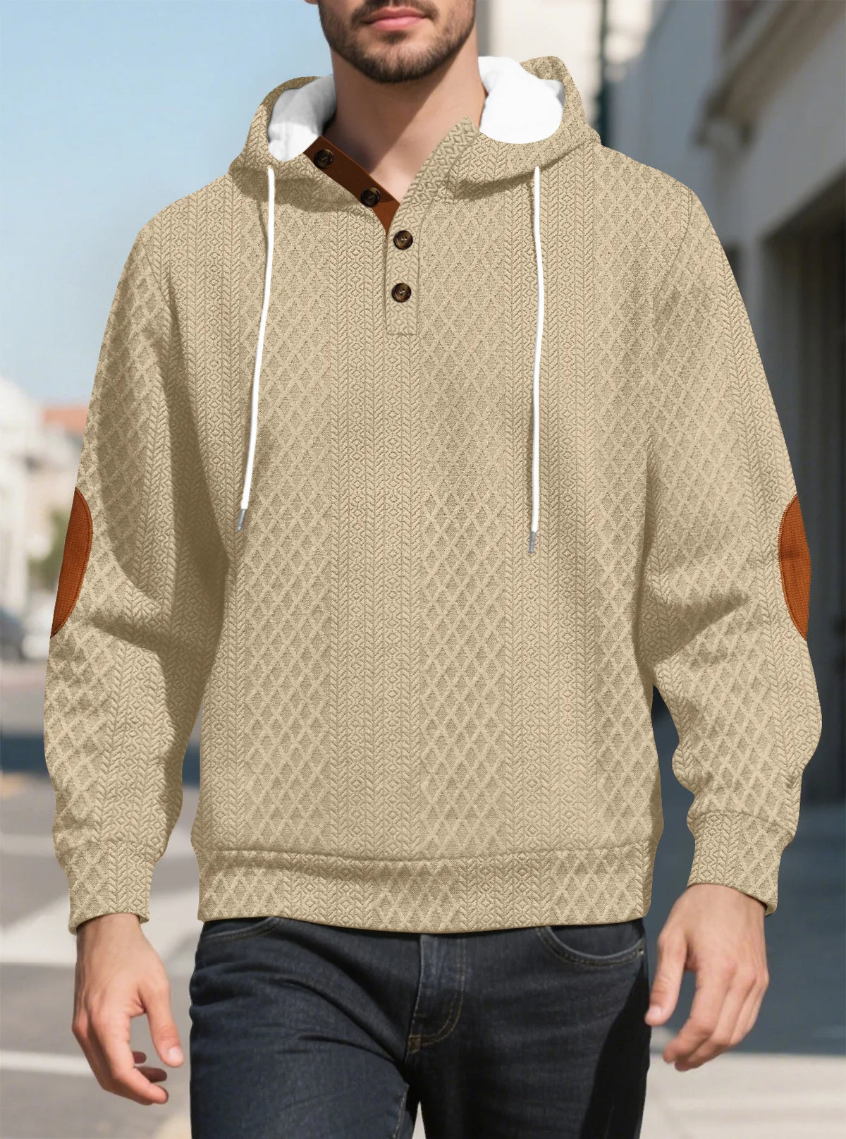 Beige diamond-textured hoodie worn by a model walking outdoors, front view with tan elbow patches 26