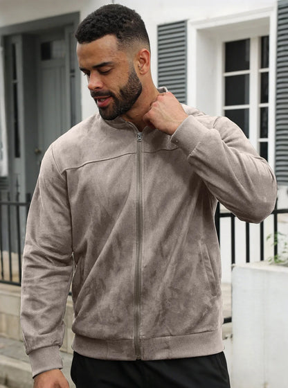 Man wearing the taupe zip-up jacket outdoors, front view, one hand raised to his collar 27