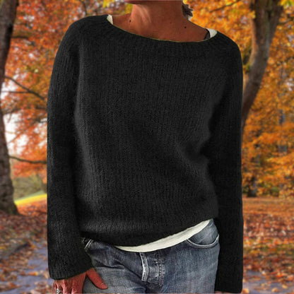 Model in the black version of the knit jumper, worn over a white top and jeans in an autumn park. 2