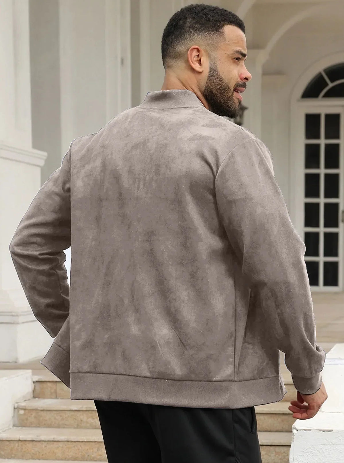Man seen from behind wearing the taupe jacket, standing on steps near white columns 28