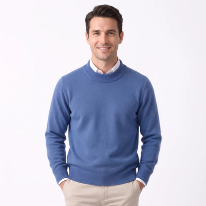 Smiling man wearing the mid blue knitted jumper over a white shirt and beige trousers 29