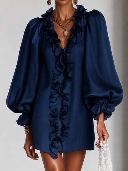 Close-up of the navy dress on a model, showing the layered ruffles down the front opening and the voluminous gathered sleeves. 6