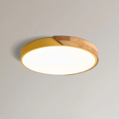 Yellow and wood round ceiling light shown close up on a plain ceiling, lit 14