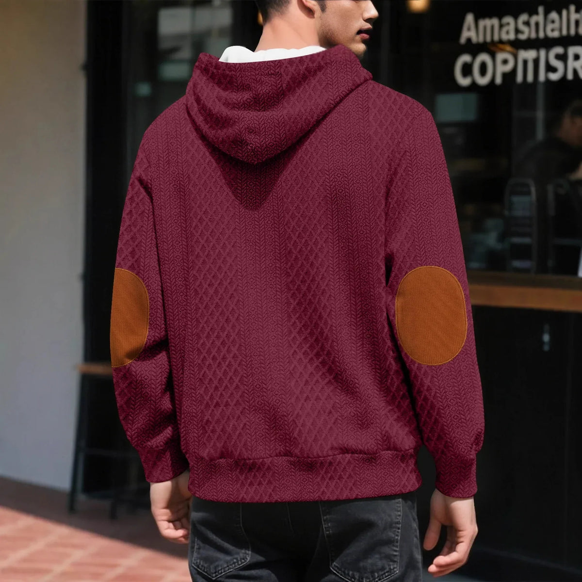 Back view of a burgundy textured hoodie worn outdoors, showing large tan elbow patches and ribbed hem 2