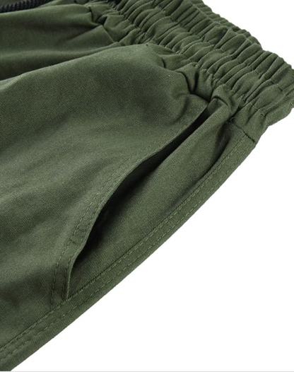 Close-up of the olive green elasticated waistband and a stitched side pocket opening. 13