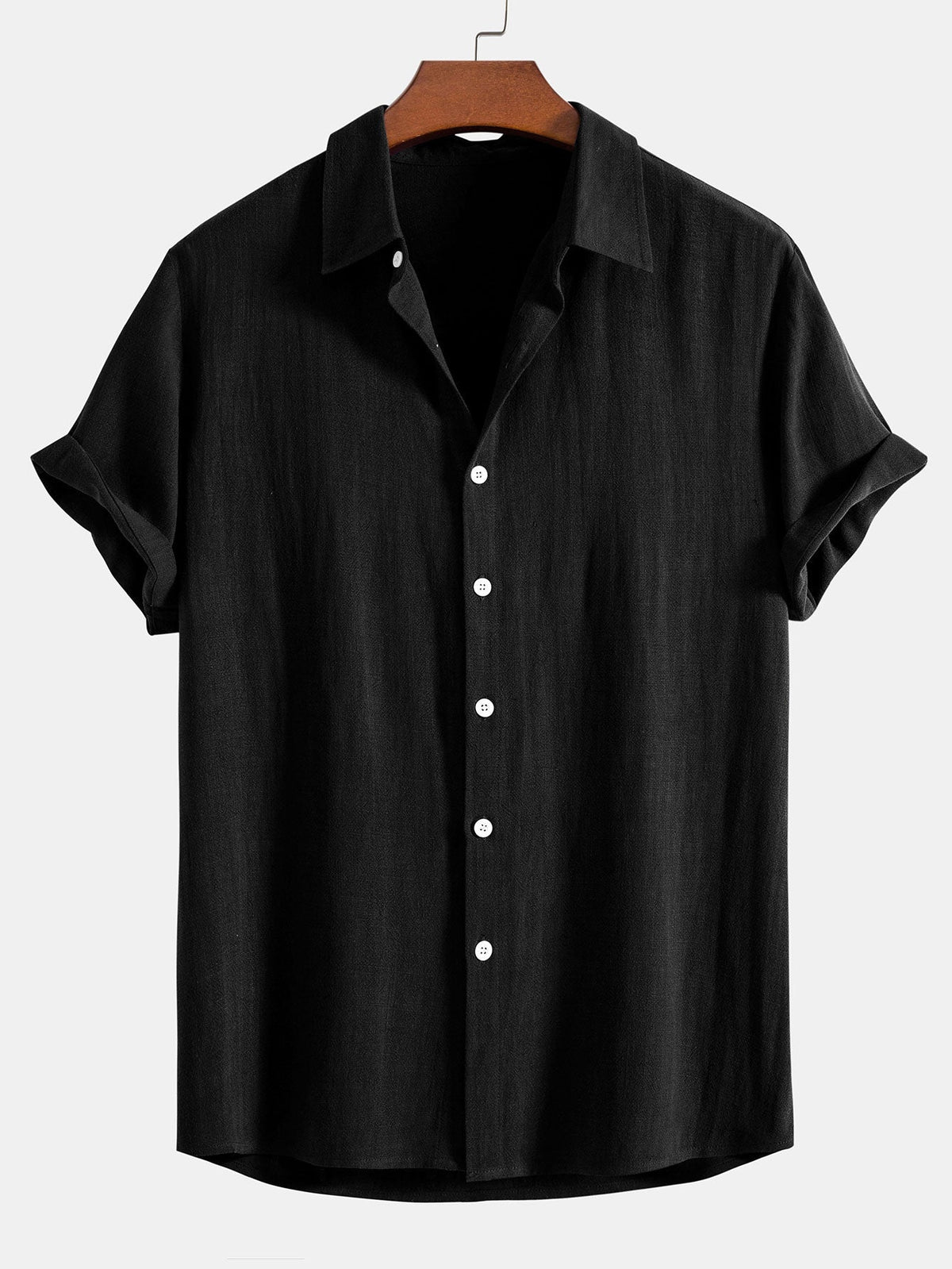 Short sleeve button-up shirt in black on a wooden hanger, showing the textured weave and white buttons. 2