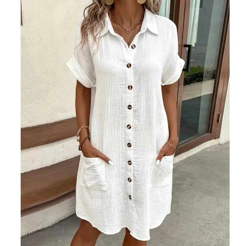 White textured shirt dress with horn buttons and rolled sleeves, worn outdoors with hands in pockets 2