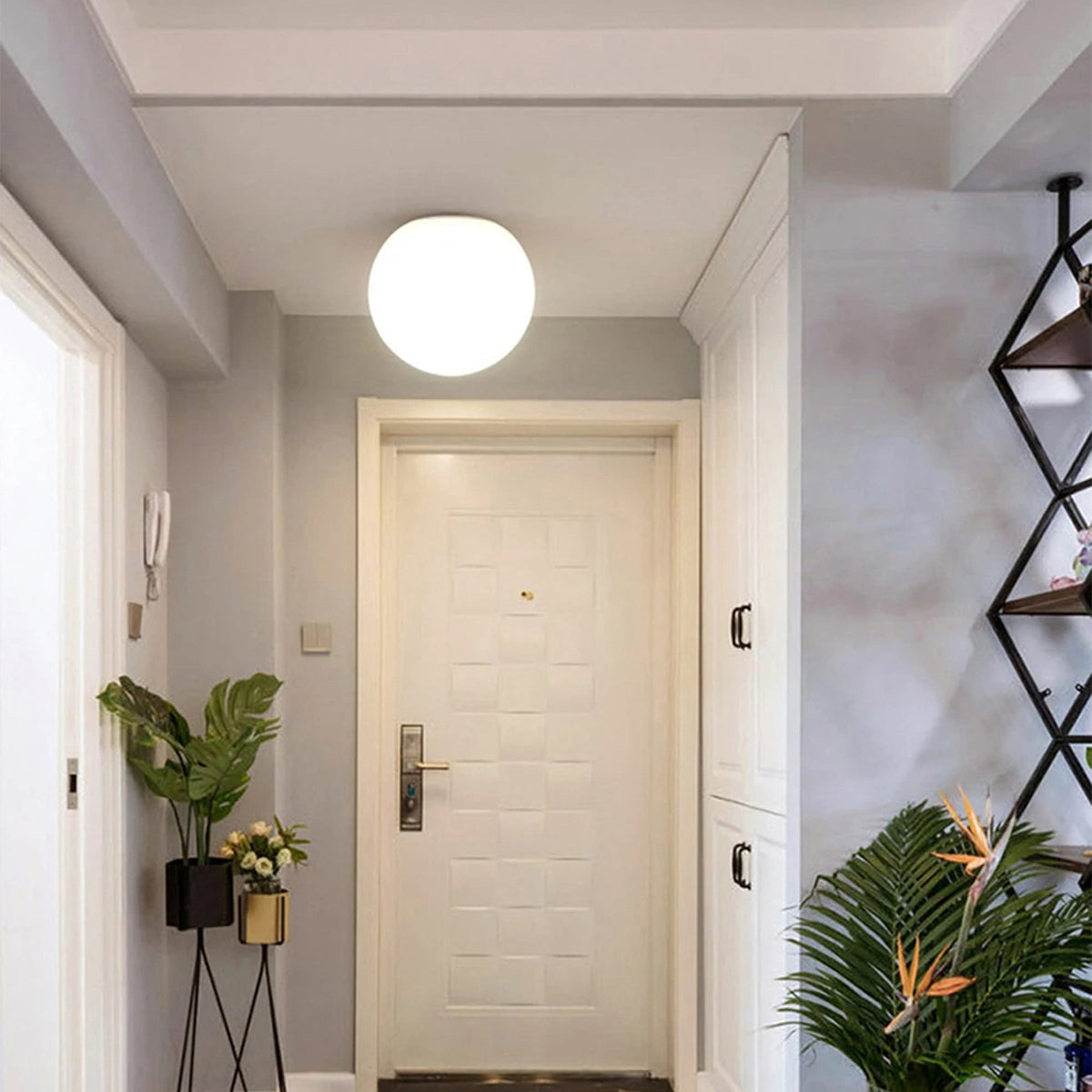 Large opal glass sphere lit on the ceiling of a bright entrance hall facing a cream door 5