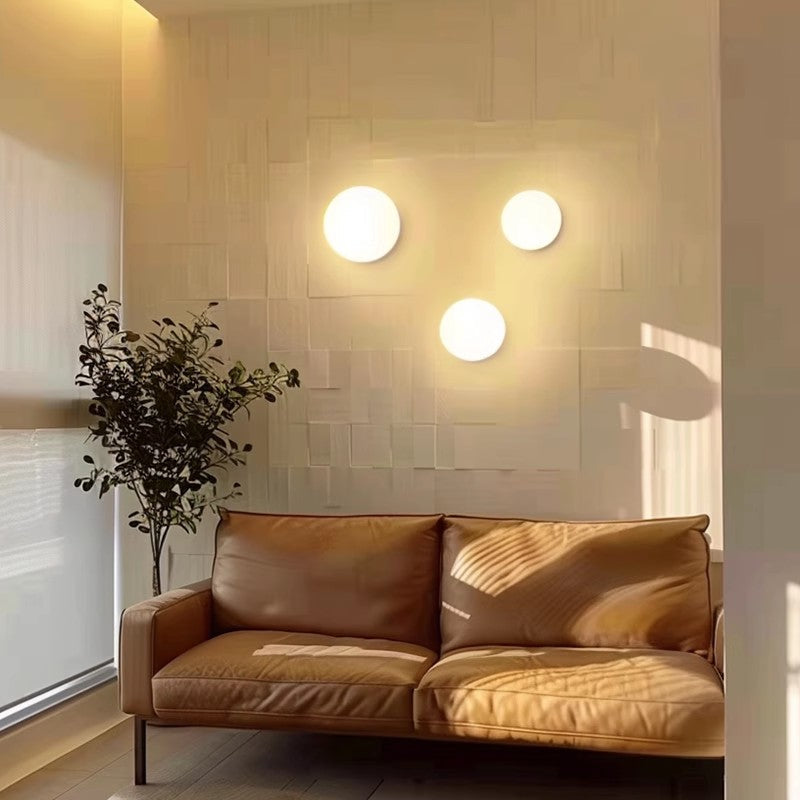 Three glowing glass spheres arranged on a textured wall above a tan leather sofa 13