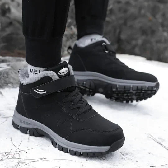 Person wearing black fleece-lined boots with dark trousers, standing on snow 4