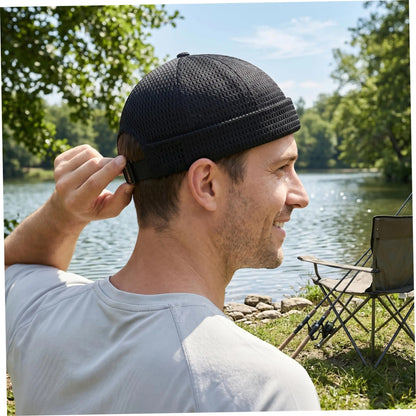 Man at a lakeside adjusting the strap of the black mesh cap at the back 2