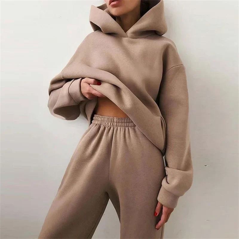 Close crop of a model in a beige hoodie and elasticated trousers, lifting the hem 2