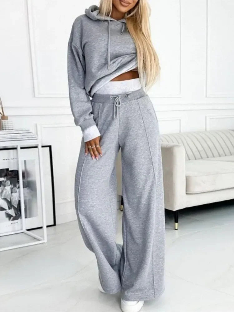 Model wearing the grey marl hoodie and wide-leg trousers with a white waistband, in a bright room 2