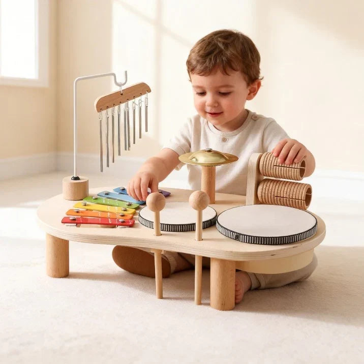 Smiling toddler in a cream top sits at the low table, playing the xylophone 3