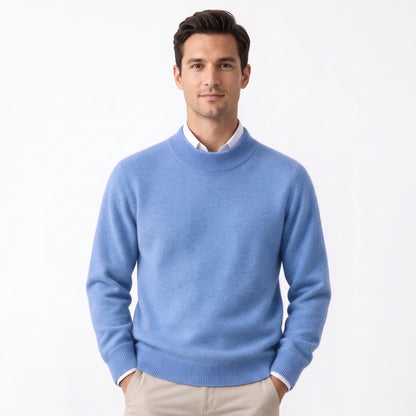 Man wearing the cornflower blue knitted jumper over a white collared shirt, standing with hands in pockets 30