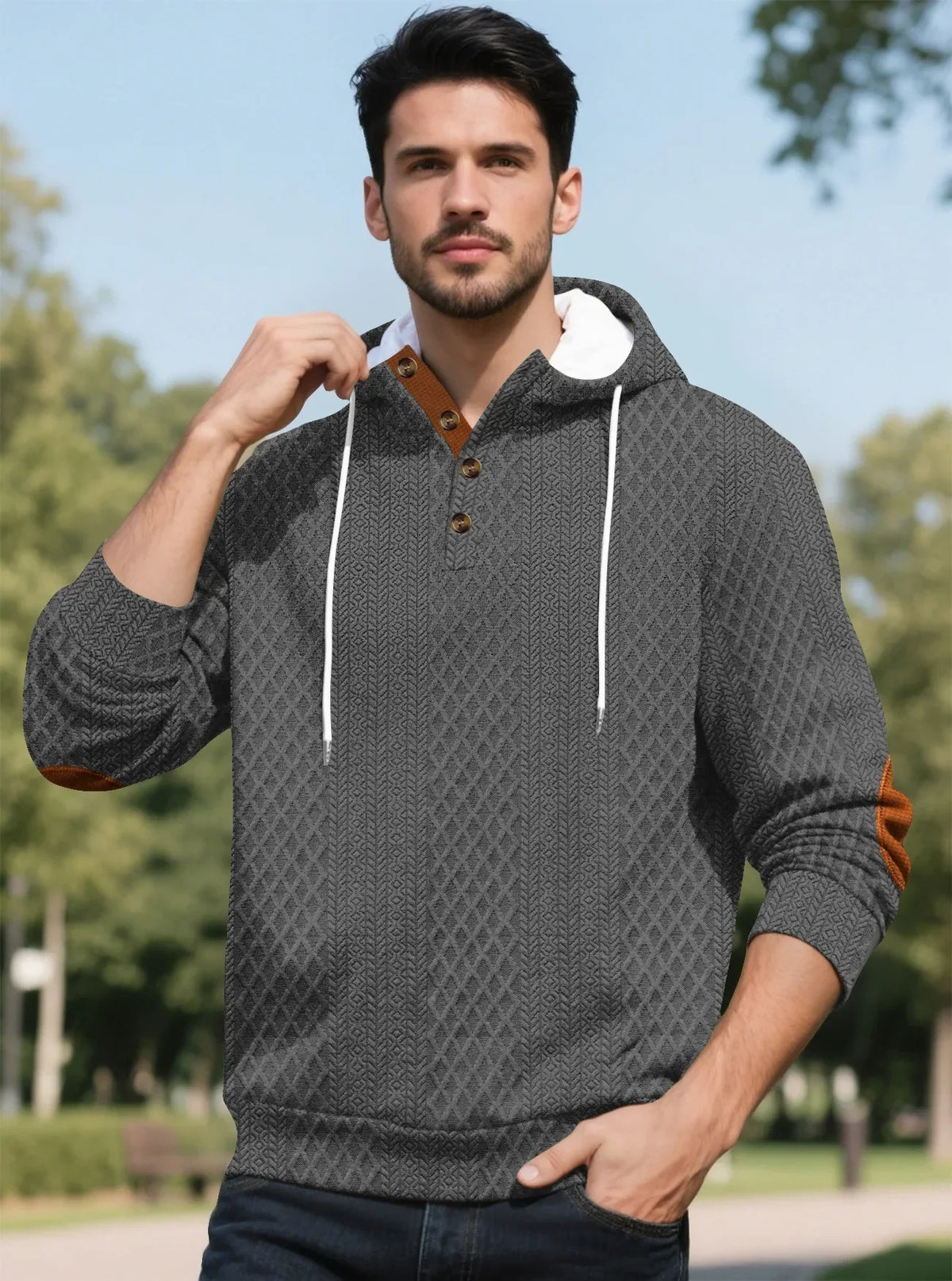 Model in grey textured hoodie posing in a park with one hand in pocket 33