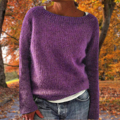 Model in the purple version of the soft knit jumper, layered over a white top with jeans in an autumn park. 7