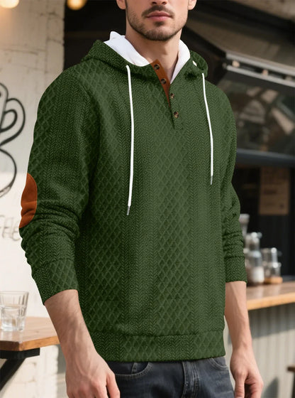 Olive green textured hoodie worn by a model in three-quarter view outside a cafe 34