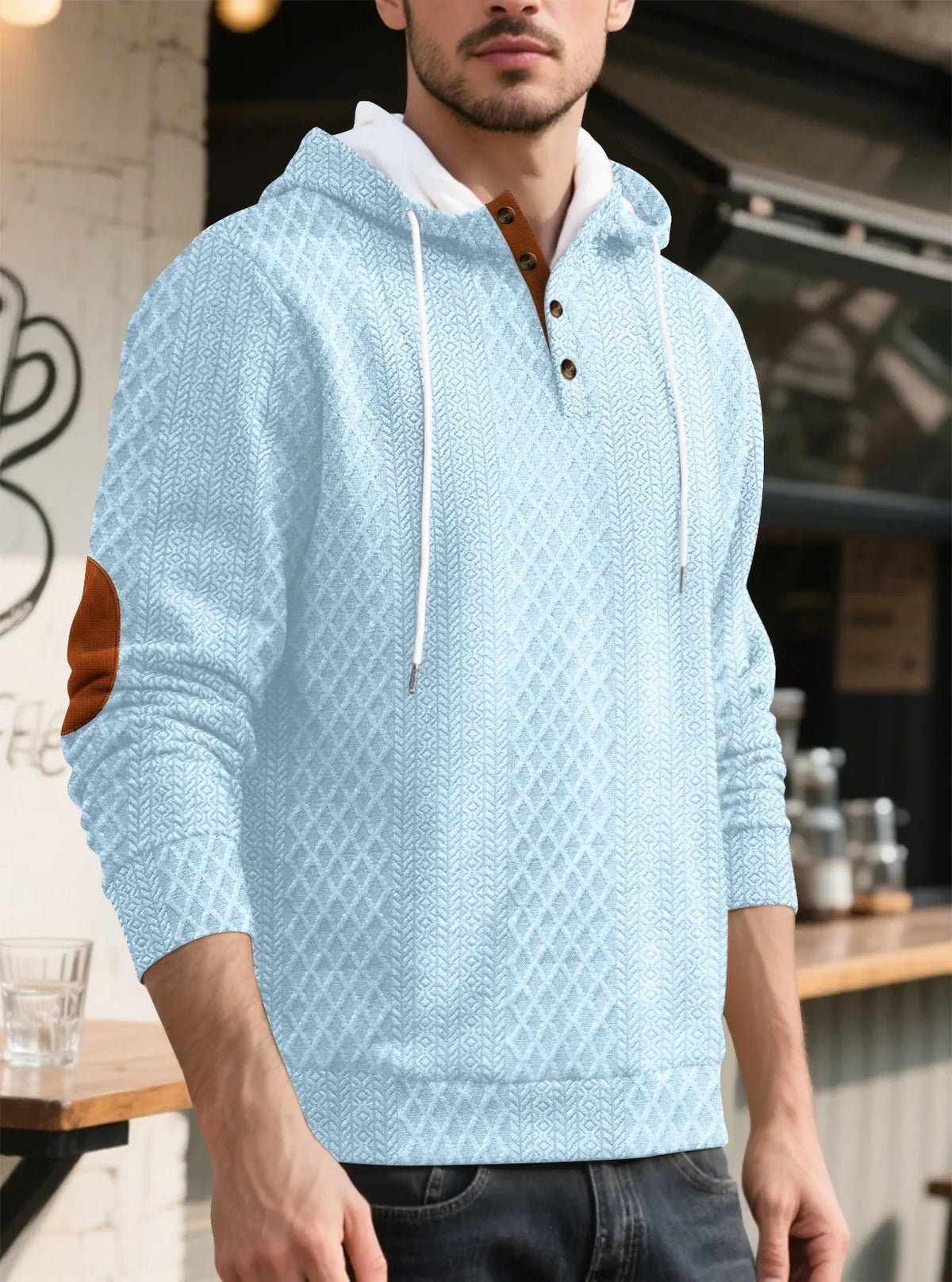 Light blue textured hoodie worn by a model in three-quarter view outside a cafe 35