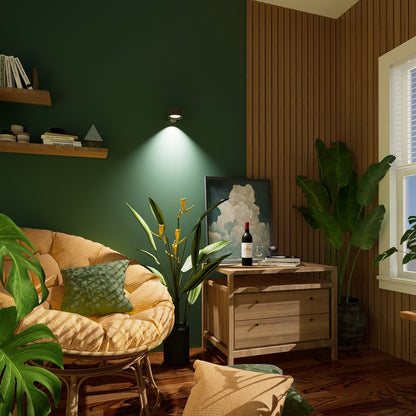 Wall light on a dark green wall in a reading corner, with a round cushioned chair, plants and a wooden side table. 9