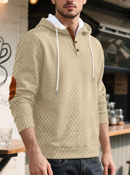 Beige textured hoodie worn by a model in three-quarter view outside a cafe 36