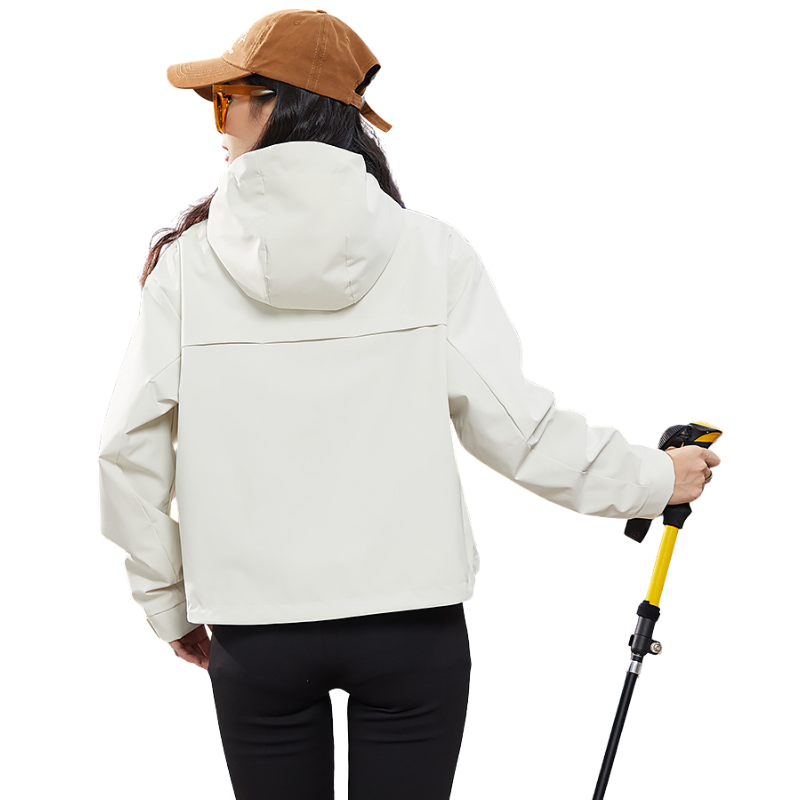 Back view of the cream jacket showing the hood and seam, woman holding a trekking pole 5