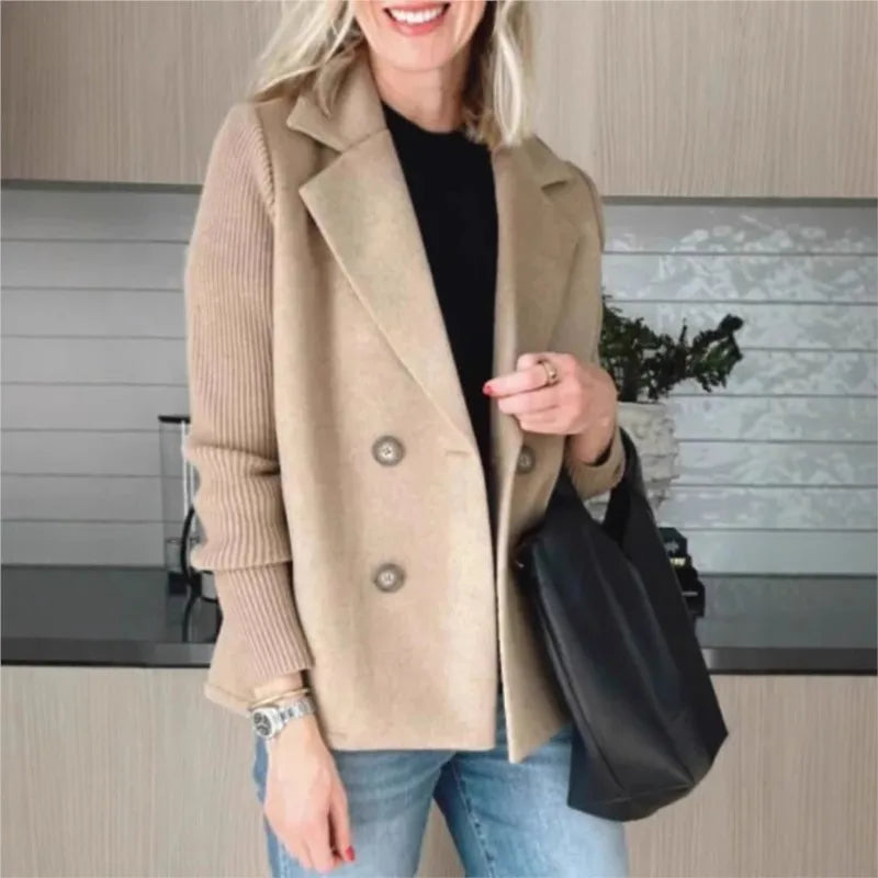 Beige double-breasted jacket with ribbed sleeves, worn smiling with a black tote bag in a kitchen 3