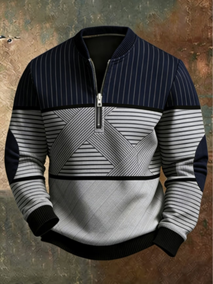 Half-zip jumper in navy and grey with pinstriped yoke, geometric striped middle panel, elbow patches and black ribbed cuffs, shown against a weathered backdrop. 1