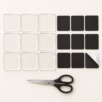 Nine clear square acrylic blanks with nine black magnet sheets and a pair of scissors on a cream background 9