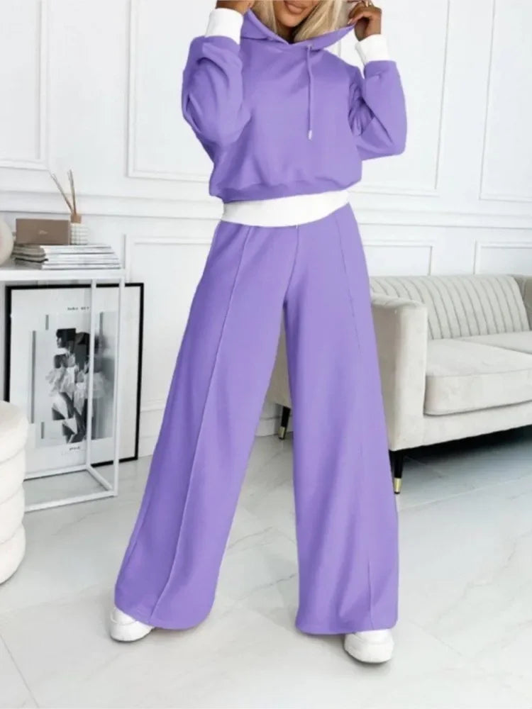 Model in the lilac hooded set with white cuffs and waistband, standing in a white room 3
