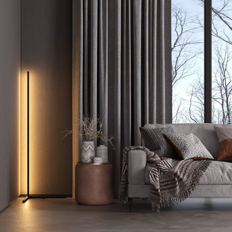 Slim black lamp casting warm light on a timber wall beside a grey sofa and curtains 3