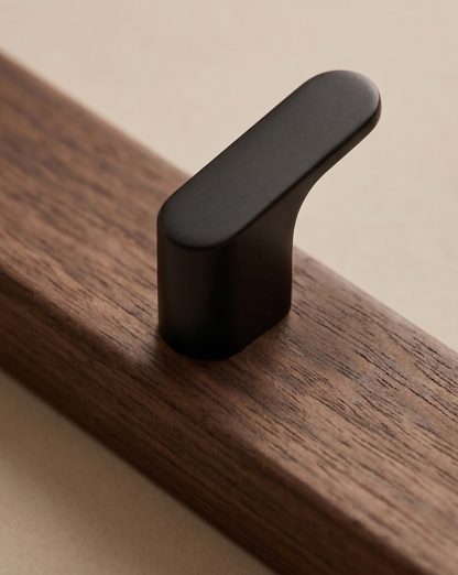 Close-up of one black hook fixed to the dark wood board, showing the grain 3