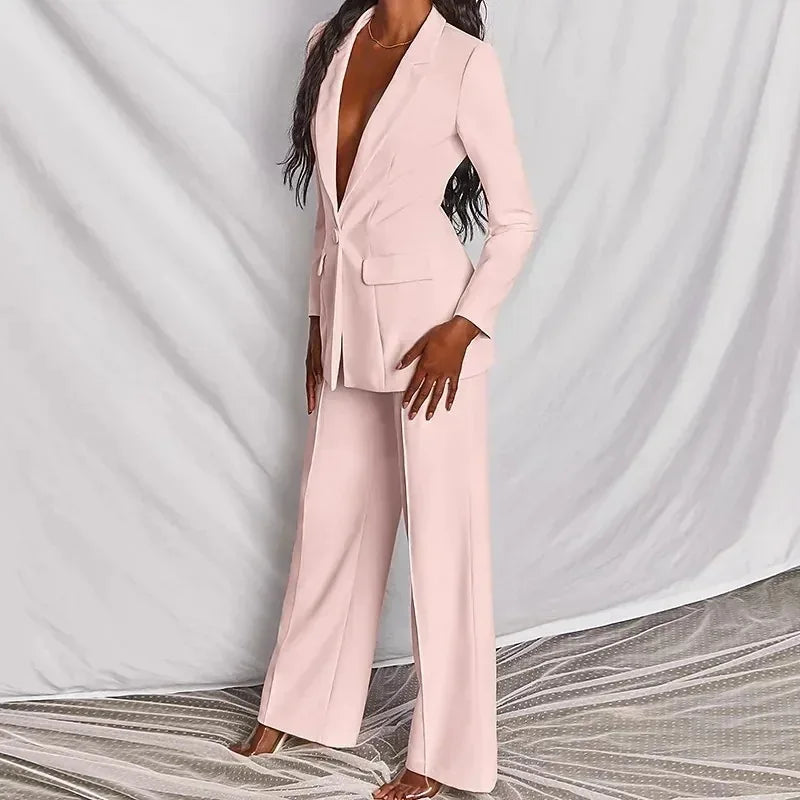 Pale pink blazer and wide-leg trousers shown from a three-quarter angle against draped grey fabric 3
