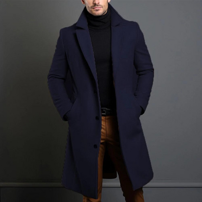 Model wearing the navy version of the longline coat with wide notch lapels, hands in pockets, over a black roll-neck. 4
