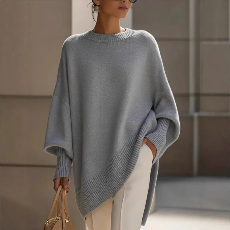 Grey jumper with batwing sleeves and ribbed cuffs, styled with white trousers and a beige handbag 3