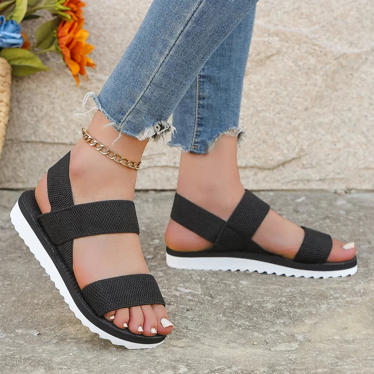 Black sandals seen from the side on a model, showing the crossed back strap and white sole 3