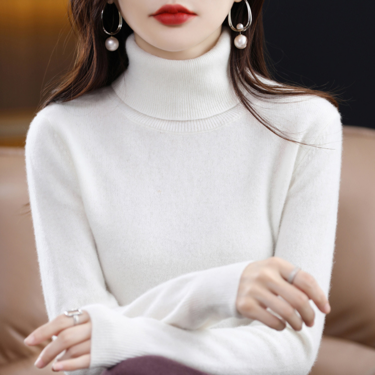 Cream-white roll-neck jumper on a seated model with crossed arms, showing the chunky ribbed collar and soft brushed surface. 12