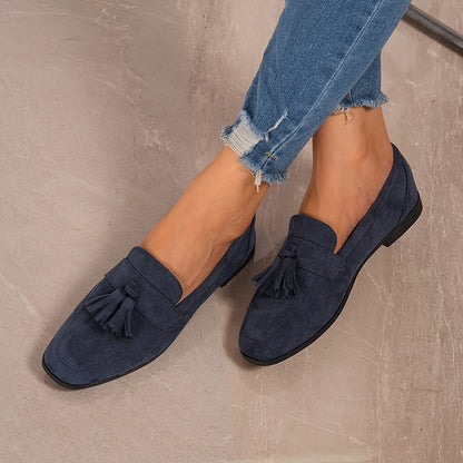 Navy tasselled loafers worn with frayed jeans, shot from above on a marbled surface 7