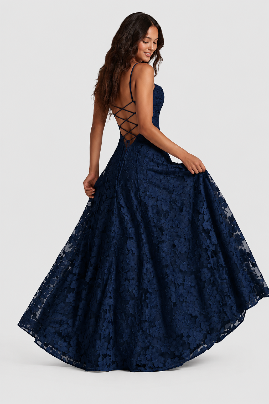 Model looking down over her shoulder in a navy lace gown, showing criss-cross lacing at the open back. 5