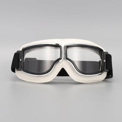 Front view of the goggles with cream-white padding, chrome-trimmed frame, clear lenses and a black elastic strap. 13