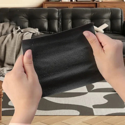 Both hands hold up a black leather-grain patch in front of a dark sofa 4