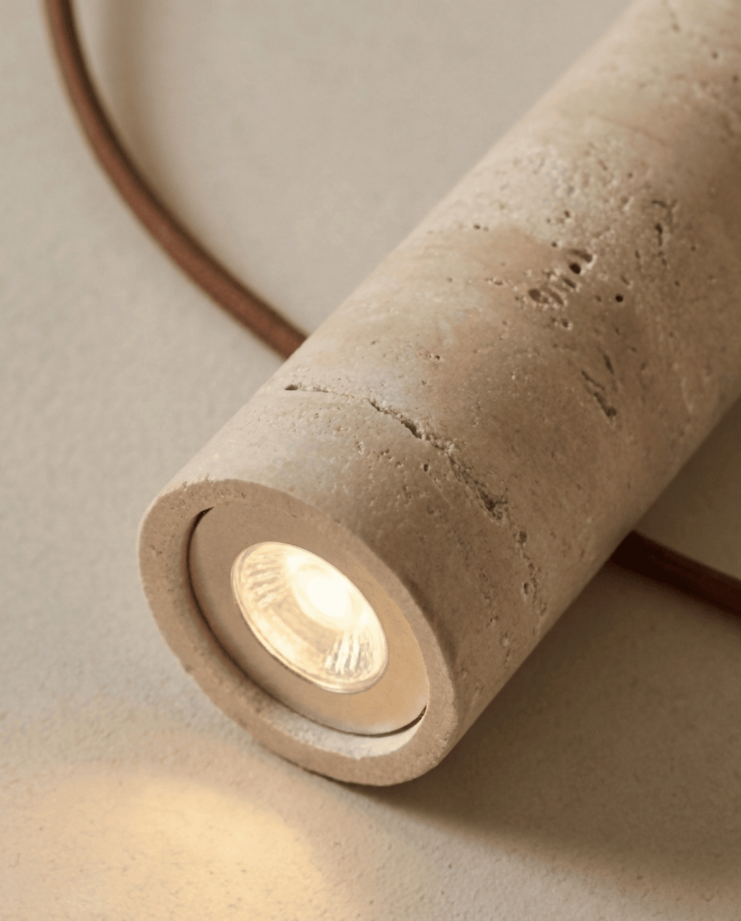 Close-up of the lit bulb inside the open end of the stone cylinder, showing its pitted surface 4