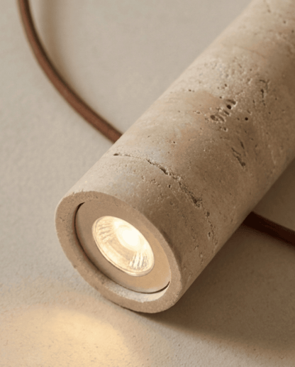 Close-up of the lit bulb inside the open end of the stone cylinder, showing its pitted surface 4