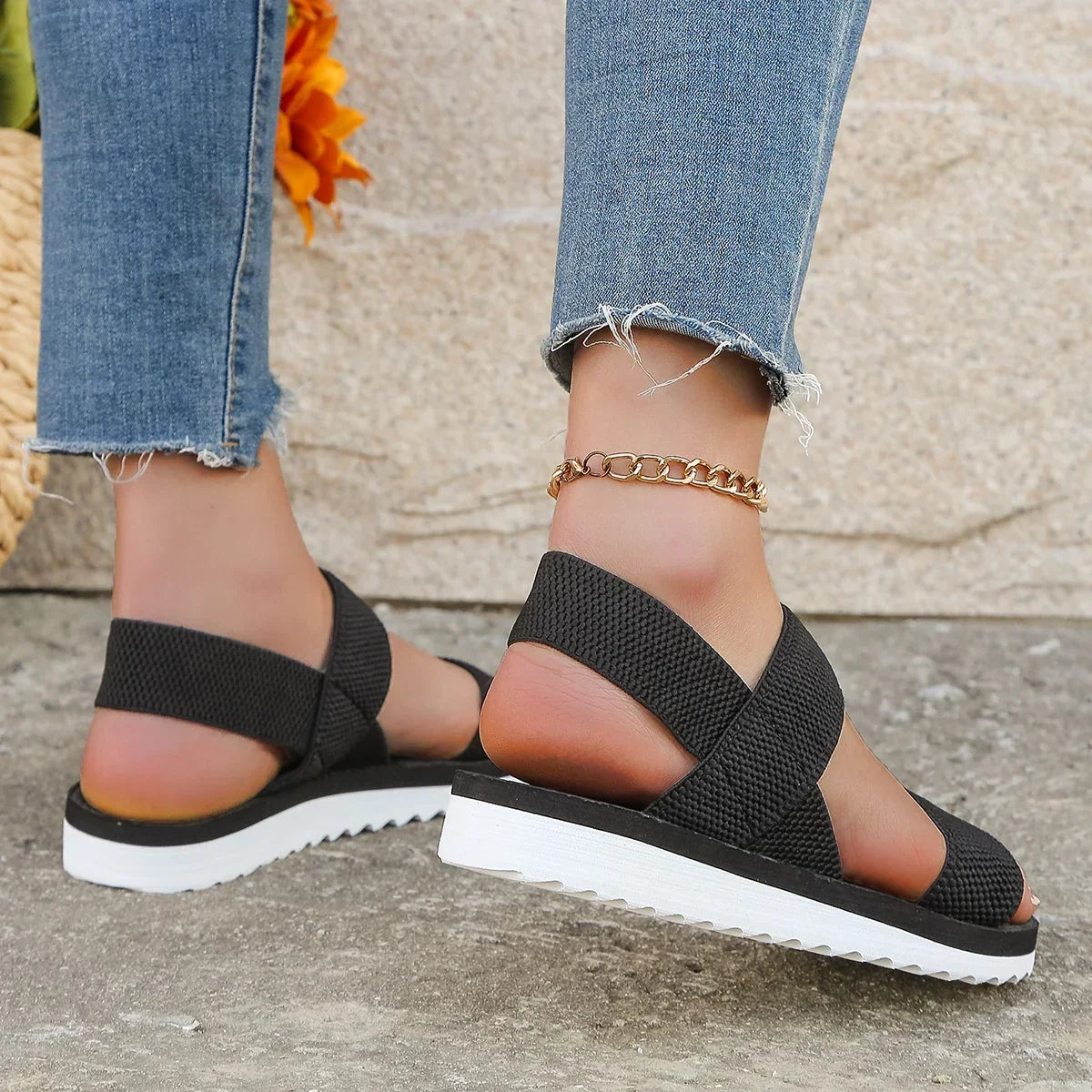 Rear view of black sandals on a model, showing the elastic heel straps and ridged white sole 4
