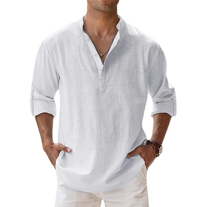 Man wearing the Henley shirt in white, with a short button placket, rolled sleeves and hands in cream trouser pockets. 4