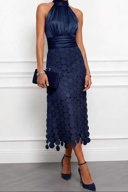 Model wears the halter midi dress in navy blue with a ruched satin bodice, disc appliqué skirt, velvet clutch and ankle-strap heels. 4