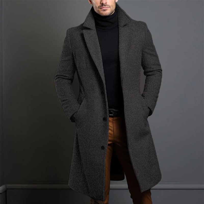 Model wearing the dark grey, textured-weave version of the longline coat, buttoned at the front over a black roll-neck. 3