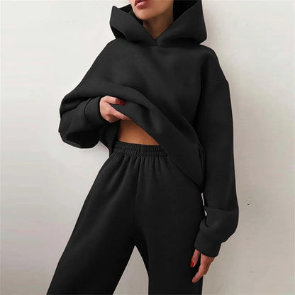 Close crop of a model in a black hoodie and elasticated trousers, holding up the hem 4